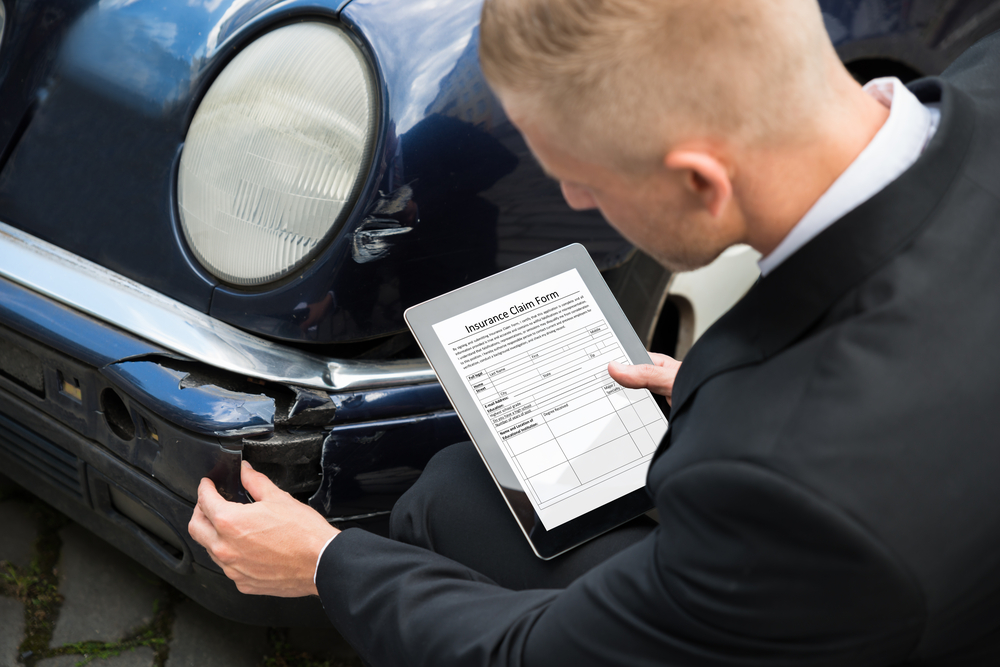 Insurance adjuster at scene of car accident in Virginia with claim form